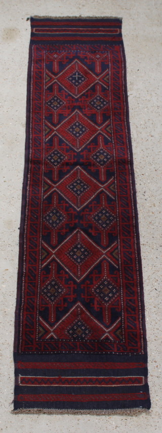 A red and blue ground Meshwani runner with 4 stylised diamonds to the centre within a multi row border 94" x 23" 