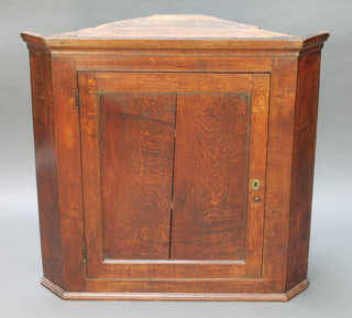A Georgian oak hanging corner cabinet with moulded cornice enclosed by a panelled door 35 1/2"h x 36"w x  17" 