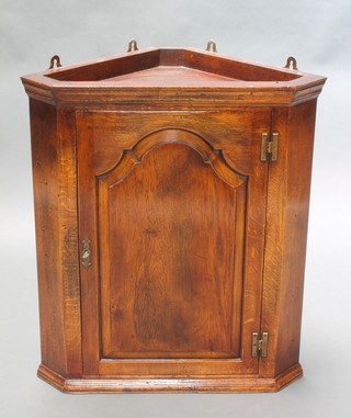 An 18th Century style oak hanging corner cabinet with moulded cornice,  fitted shelves enclosed by arched panelled door  30"h x 26"w x 14"d 