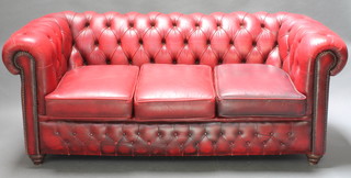 A 3 seat Chesterfield settee upholstered in red buttoned leather raised on bun feet 29"h x 72"w x 34"d