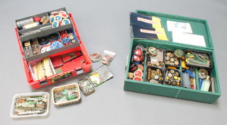 A red plastic box with cantilever interior containing various green and red Meccano together with a green painted shallow wooden box containing various Meccano wheels etc 