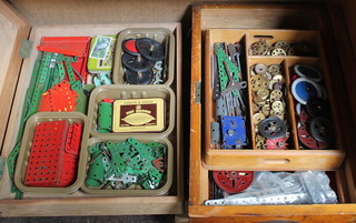 Two shallow wooden boxes containing various items of red and green Meccano, wheels etc
