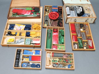 A white wooden box containing various steel coloured Meccano, a shallow box containing red and green Meccano and 5 trays of Meccano 