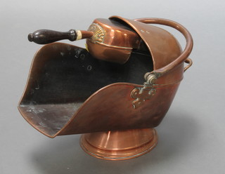 A Victorian copper helmet shaped coal scuttle complete with shovel with turned wooden handle 