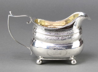 A George III silver cream jug with chased floral decoration and armorial on ball feet London 1813, 150 grams 