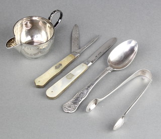 A Victorian silver cream jug with chased decoration and armorial Birmingham 1887, a pair of silver nips, a teaspoon and 2 silver bladed mother of pearl fruit knives, weighable silver 96 grams 