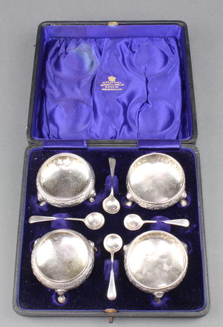 A set of 4 George IIII repousse silver salts with floral decoration on pad feet together with 4 later spoons, 166 grams, contained in a fitted case