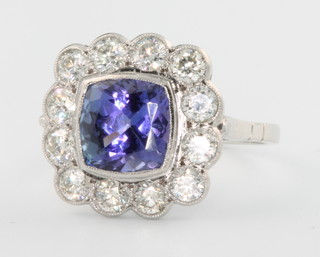 An 18ct white gold cushion cut tanzanite and diamond ring, the centre stone approx. 3ct surrounded by 12 brilliant cut diamonds approx. 1.3ct size N 1/2