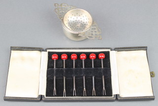 A sterling silver tea strainer and stand and a cased set of 6 sterling silver cocktail sticks 