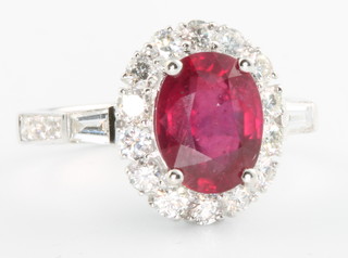 An 18ct oval white gold ruby and diamond cluster ring, the centre stone approx. 3.11ct surrounded by diamonds approx 0.84ct, size M