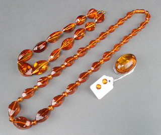 A natural amber bead necklace 28", a ditto pair of ear studs and a brooch 