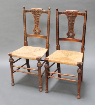 A pair of Art Nouveau carved oak splat back bedroom chairs with woven rush seats, raised on turned supports 