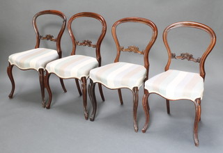 A set of 4 Victorian mahogany balloon back dining chairs with shaped mid rails and upholstered seats raised on French cabriole supports