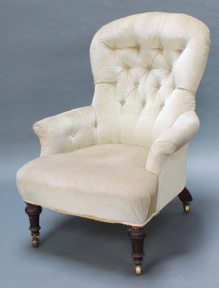 A Victorian armchair upholstered in green buttoned material and raised on turned supports
