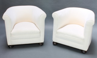 A pair of tub back armchairs upholstered white dralon, raised on bun feet 
