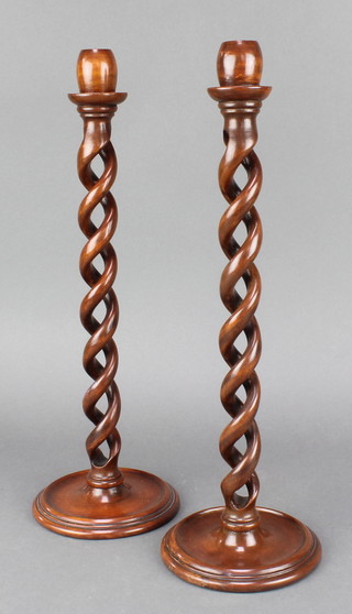 A pair of spiral turned mahogany candlesticks raised on circular bases 14 1/2" 