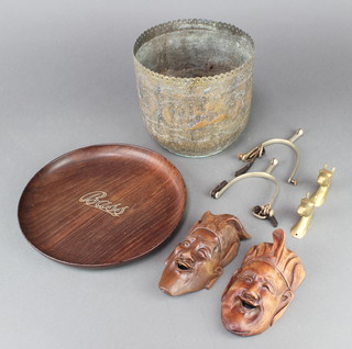 A pair of Eastern carved wooden masks 6 1/2" (missing teeth), a Sanenwood circular tray marked Bass 10",  a brass jardiniere 7" x 7", a pair of nickel spurs and 2 brass  horse head ornaments 2" 