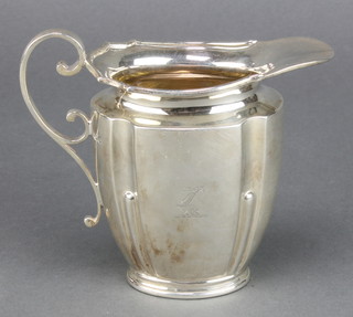 An Edwardian silver cream jug with chased armorial Sheffield 1911 