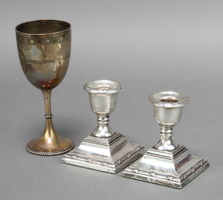 A Victorian silver cup with chased decoration London 1880 84 grams and a pair of dwarf silver candlesticks with rubbed marks 3" 