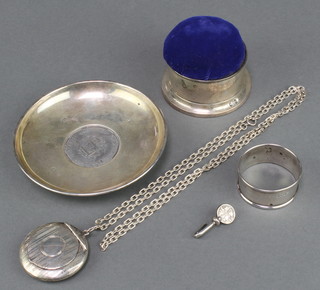 A silver dish with coin base, a pin cushion, napkin ring, compact and chain together with a tie clip 