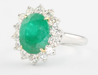 An 18ct white gold oval emerald and diamond ring, the centre stone approx 3ct surrounded by brilliant cut diamonds approx 1ct, size M 