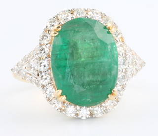 An 18ct yellow gold emerald and diamond oval cluster ring, the centre stone approx 6.93ct surrounded by brilliant cut diamonds approx. 0.95ct, size N 