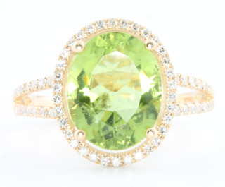 A 14ct yellow gold oval peridot and diamond ring, the centre stone 4.12ct, the brilliant cut diamonds 0.30ct size M 1/2