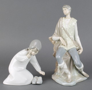 A Lladro figure of a kneeling girl with slippers 6 1/2" together with a ditto of a fisherman 10 1/2" 