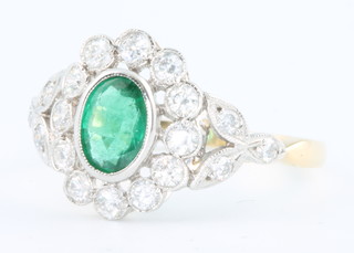 An 18ct yellow gold oval emerald and diamond ring, the centre stone approx. 0.6ct surrounded by brilliant cut diamonds approx. 0.8ct size O 