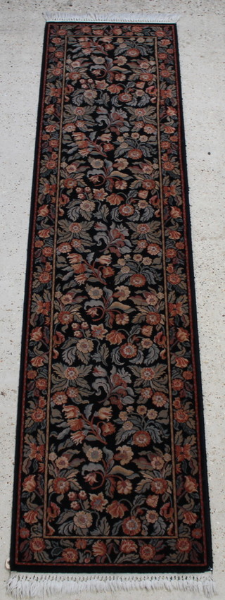 A black and floral ground machine made Persian style runner 107" x 27" 