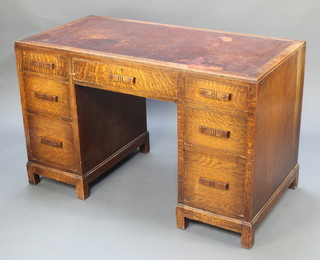 An Art Deco oak kneehole desk with brown leather writing surface fitted 1 long drawer flanked by 6 short drawers, raised on square supports with bracket feet 30"h x 48"w x 24"d  