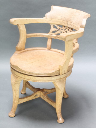 An Edwardian bleached oak revolving tub back office chair raised on cabriole supports 
