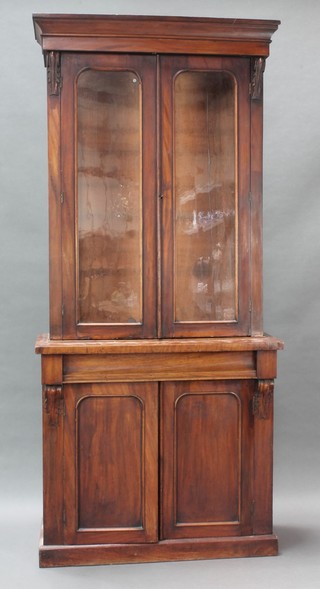 A Victorian mahogany bookcase on cabinet, the upper section with moulded cornice fitted adjustable shelves enclosed by arched panelled doors, the base fitted 1 long drawer above a double cupboard enclosed by arched panelled doors, raised on a platform base 77 1/2"h x 35"w x 15"d 