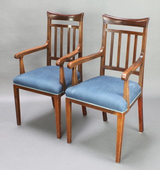 A pair of Art Nouveau Liberty style mahogany stick and rail back open armchairs with upholstered seats raised on square tapered supports