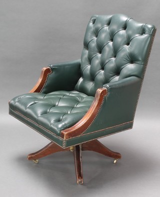 A revolving office chair upholstered in green buttoned leather 