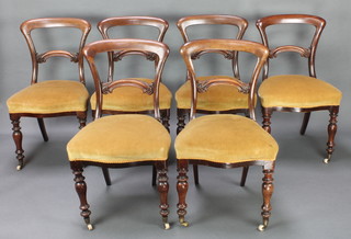 A set of 6 Victorian mahogany spoon back dining chairs with carved mid rails, the seats upholstered in yellow material, raised on turned supports 