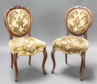 A set of 6 Victorian carved walnut show frame balloon back dining chairs, the seats of serpentine outline, raised on cabriole supports, upholstered in gold floral velour