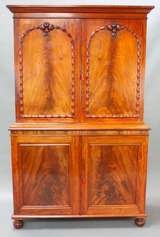 A Victorian mahogany press cabinet, the associated upper section with moulded cornice, fitted shelves enclosed by a pair of arched panelled doors with crests carved fruit, the base fitted a cupboard fitted 3 trays enclosed by panelled doors, raised on bun feet 77 1/2"h x 49 1/2"w x 21"d