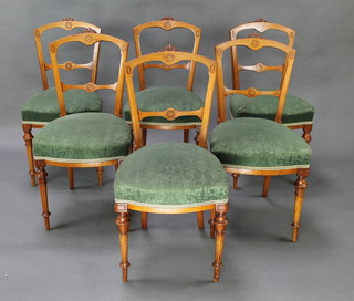 A set of 6 Victorian carved and inlaid mahogany bar backed dining chairs with shaped mid rails and over stuffed seats, raised on turned supports 