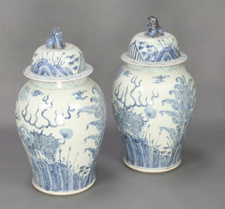 A pair of 20th Century Chinese antique style baluster jars and covers decorated with dragons having lion finials 24" 