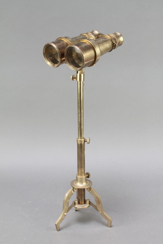 A pair of Victorian style brass binoculars raised on a tripod stand 
