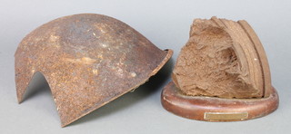 A large section of shrapnel mounted on an oval mahogany plaque marked 1 1st C.S 13-2-30 4"h x 6" x 4" together with a section of recovered First World War steel helmet 9" 