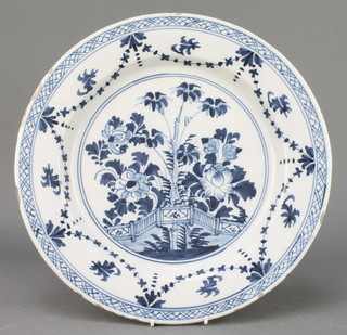 An 18th Century English blue and white Delft ware plate decorated with stylised tree and flowers, the border with swags and flowers 13 1/2" 