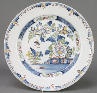 An 18th Century English Delft ware polychrome plate decorated with a garden view within a geometric border 14" with Gerald Bushell Collection label 