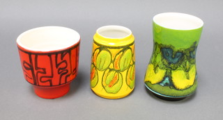 A 1970's Poole Pottery red ground jardiniere no.78 4 1/2", a yellow ground tapered ditto decorated with fruit no.34 5" and a waisted green do. no. 83 by Anita Lawrence 6" 