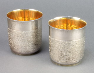 A pair of chased silver beakers with gilt interiors London 1982, 311 grams 