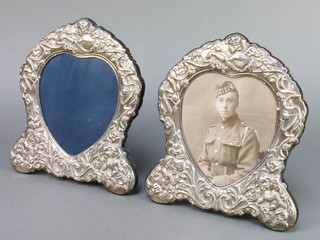 A pair of Sterling repousse silver heart shaped photograph frames decorated with cavorting cherubs 8 1/2" 
