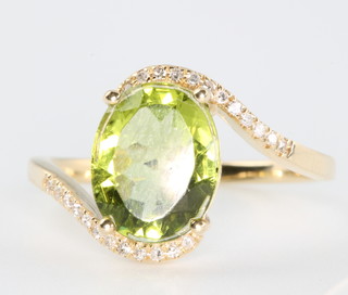 A 14ct yellow gold oval peridot and diamond ring, the centre stone approx. 2.4ct, the diamonds approx 0.3ct, size M