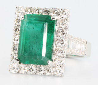 An 18ct white gold Art Deco style emerald and diamond rectangular ring, the centre stone approx. 7.73ct surrounded by brilliant and baguette cut diamonds approx. 1.67ct size O 