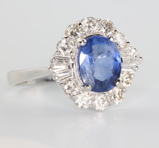 An 18ct white gold oval sapphire and diamond ring the centre stone approx 2.06ct, surrounded by brilliant and tapered baguette cut diamonds approx. 0.91ct size N